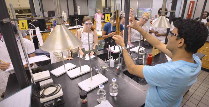 Students conducting chemistry experiments in a college lab setting.