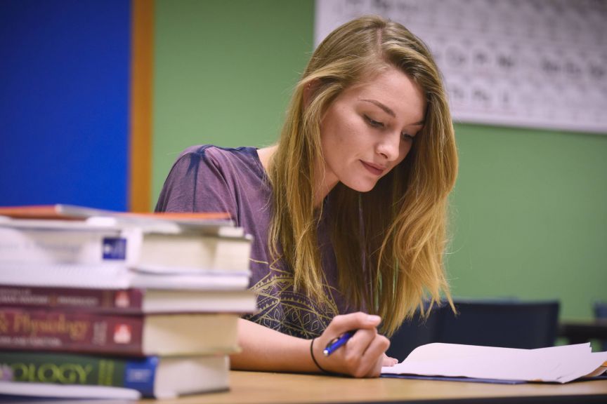 College student studying with textbooks and notes for higher education success.
