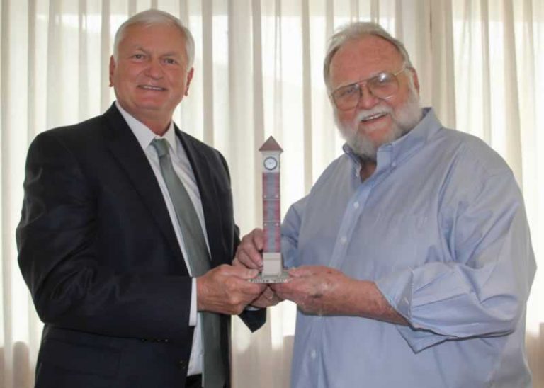Two men exchanging a service award trophy during PSC honors event.