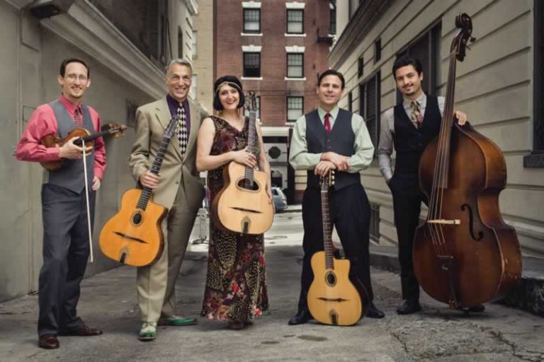 Jazz band performing outdoors in an urban alleyway with guitars and double bass.
