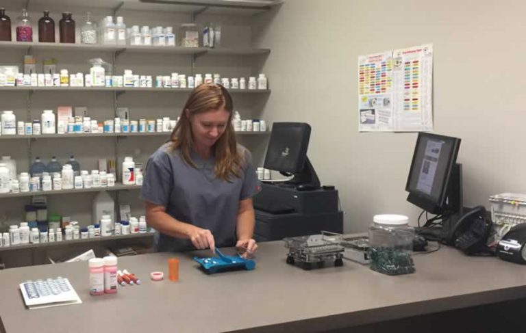 Pharmacy technician student organizing medication bottles in a pharmacy lab.
