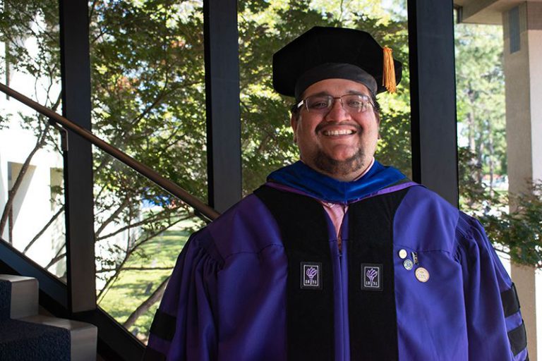 Smiling graduate in cap and gown celebrating academic achievement at Pensacola State College.
