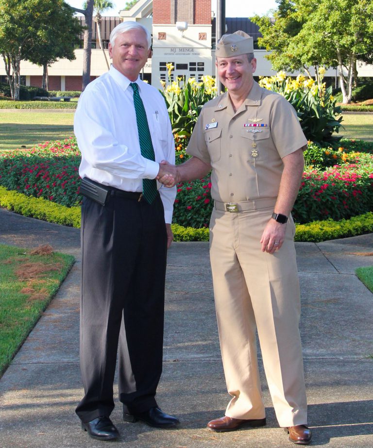 College official and military veteran shaking hands outdoors at Pensacola State College.