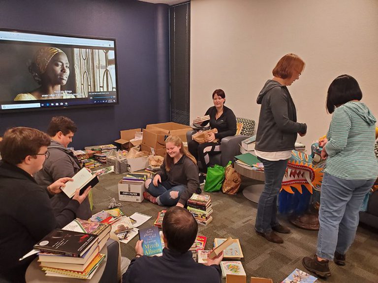 Accessible image of students and volunteers participating in the Ugandan Book Drive for Robinson Hon.