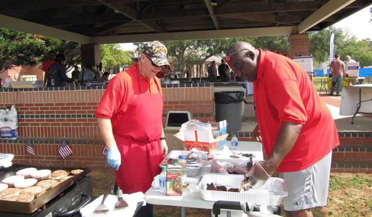 Veterans Day celebration with college staff serving food at a cookout honoring veterans.