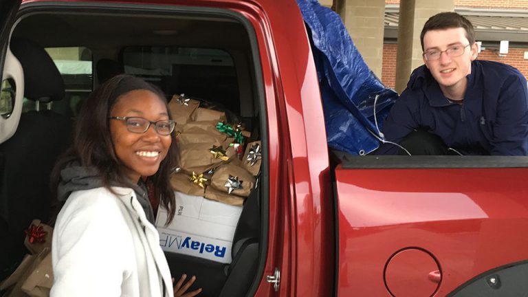 Students volunteering with donated socks, jackets, gloves, and blankets for veterans.