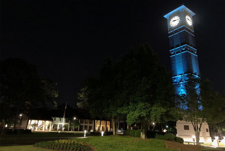Menge Tower illuminated in blue at night, paying tribute to healthcare and essential workers during.