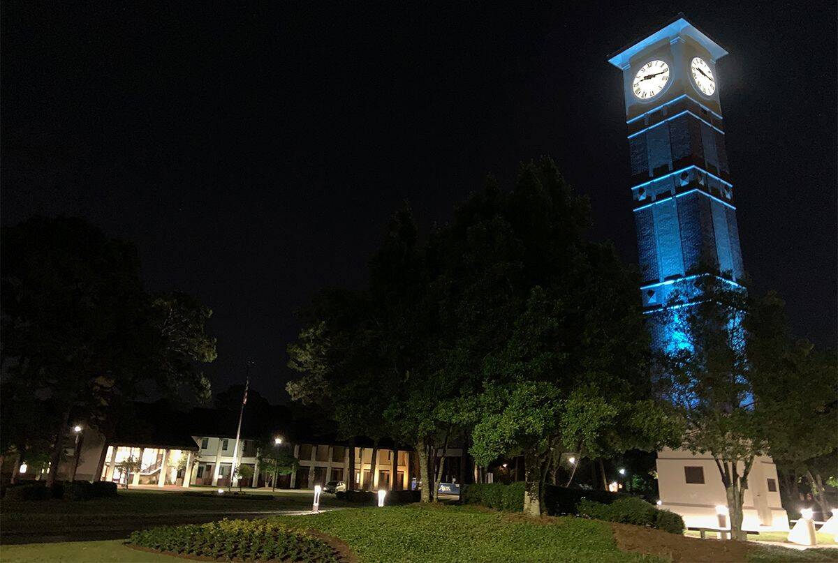 Menge Tower illuminated in blue at night, paying tribute to healthcare and essential workers during.