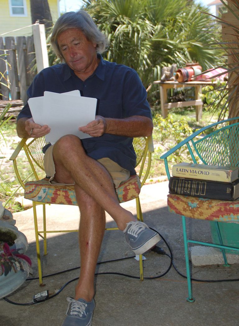Senior man reading documents in garden setting, enjoying a sunny day.