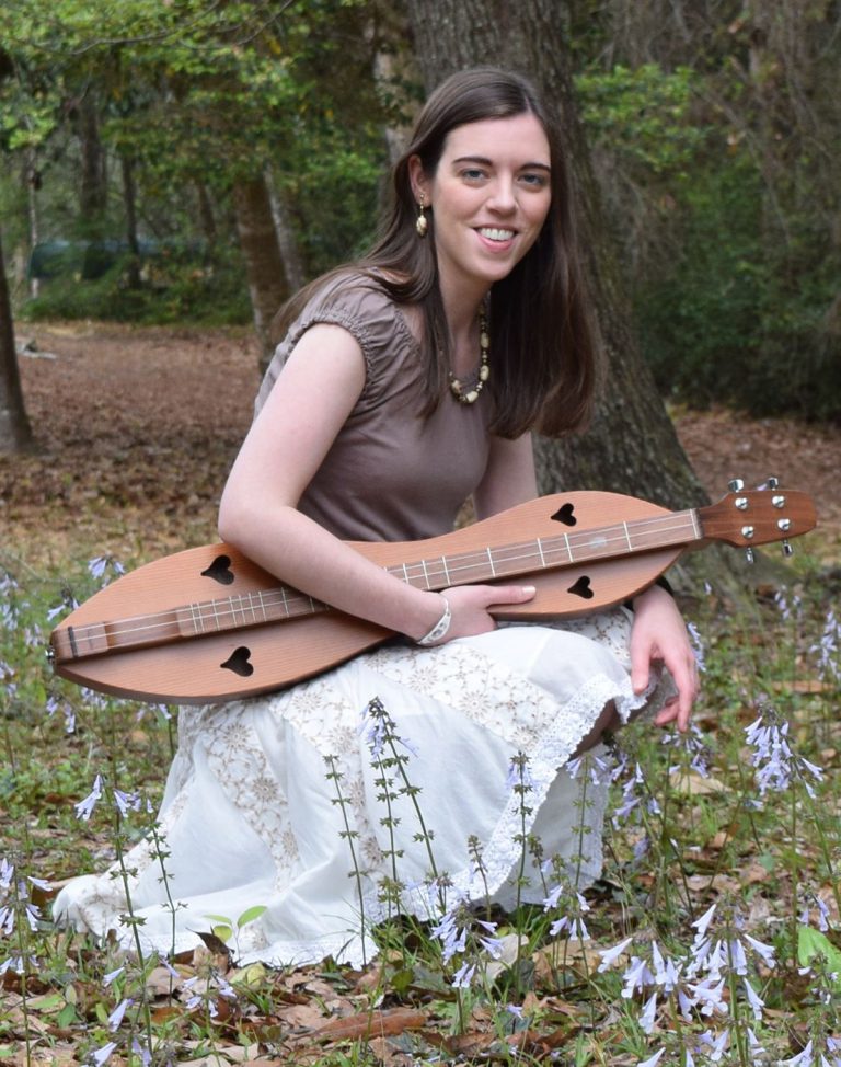Experienced music educator demonstrates mountain dulcimer playing in natural setting.