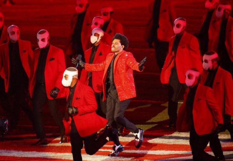Music performer in red jacket with backup dancers in red suits and masks during Super Bowl LV halfti.