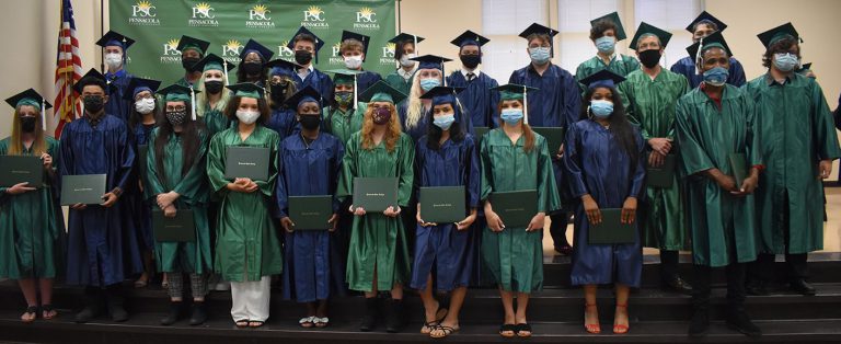 GED graduates at Pensacola State College wearing caps and gowns, holding diplomas, symbolizing educa.