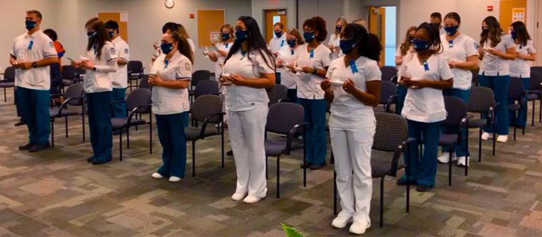 Nursing students at Pensacola State College standing in a classroom, wearing scrubs and masks, durin.
