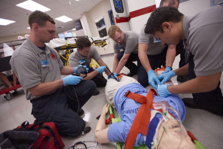 Emergency Medical Services students practicing patient care techniques in a simulation lab. EMS students performing patient care training for paramedic certification at Pensacola State College.