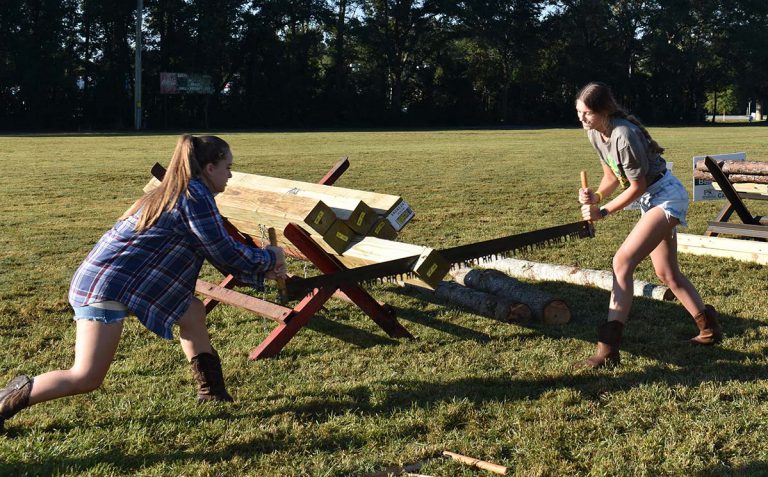 Lumberjack Festival outdoor activities at Pensacola State College Two young women competing in log sawing event at PSC Lumberjack Festival.