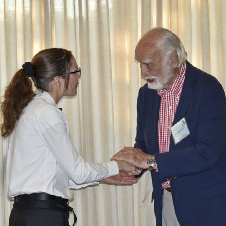 High school student receiving scholarship from college official at Pensacola State College.