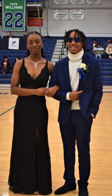 Elegant couple at college homecoming event in gymnasium.