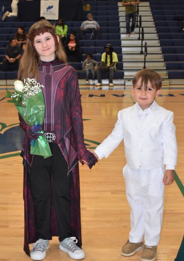 Young girl and boy in formal attire holding hands during Homecoming event.