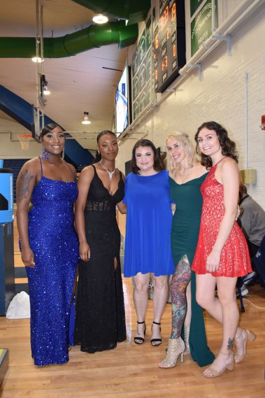 Diverse group of women dressed in elegant evening gowns at Homecoming event.