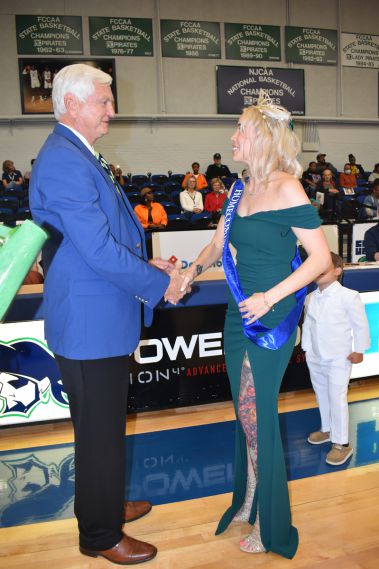 College homecoming event with student and official handshake at basketball game.