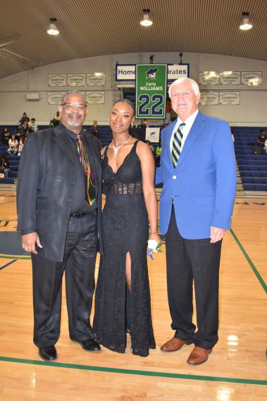 Smiling students and faculty at college homecoming event in gymnasium.