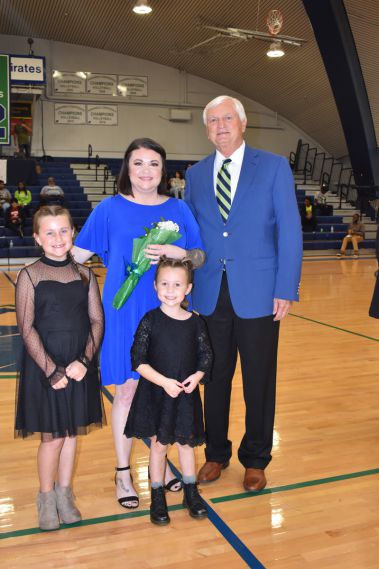 Smiling family at Pensacola State College homecoming event, with students and faculty in the backgro.