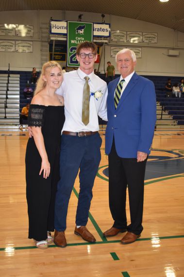 Young man in cap and gown with family during homecoming event.