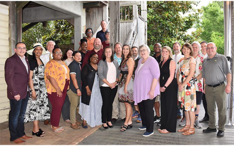 Diverse group of Pensacola State College faculty and staff members celebrating graduation from the P.