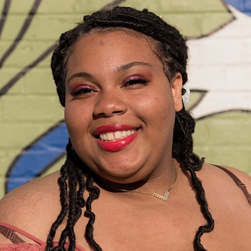 Empowered student portrait at Pensacola State College Diverse student smiling with confidence against colorful mural background.
