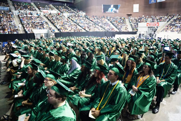 Graduates in green caps and gowns at Pensacola State College Spring commencement exercises.