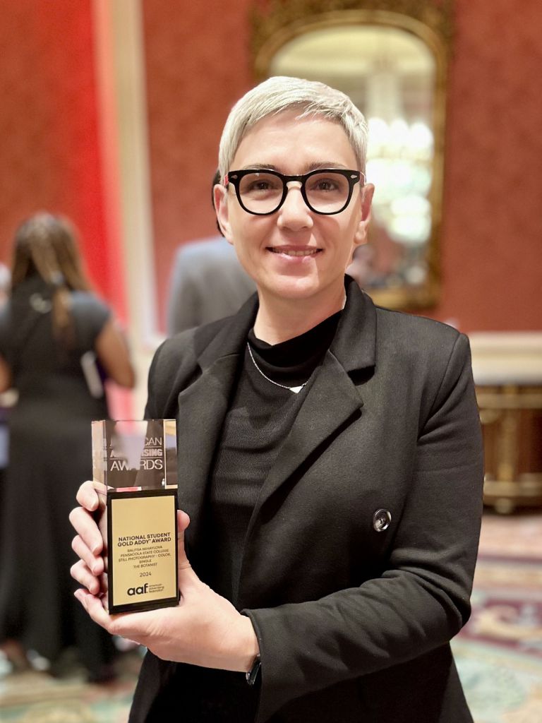 Award-winning PSC photography student holding gold ADDYs award at national competition.