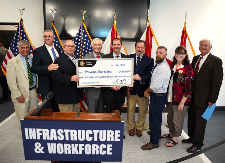 Group of officials holding a large grant check for Pensacola State's Aviation Airframe and Powerplan.