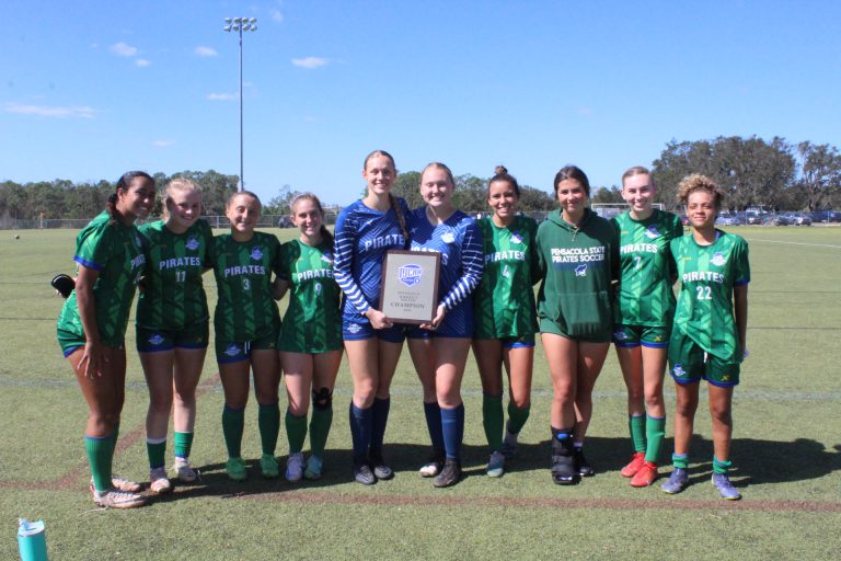 All-American Pirates soccer team with coach holding award plaque on field.