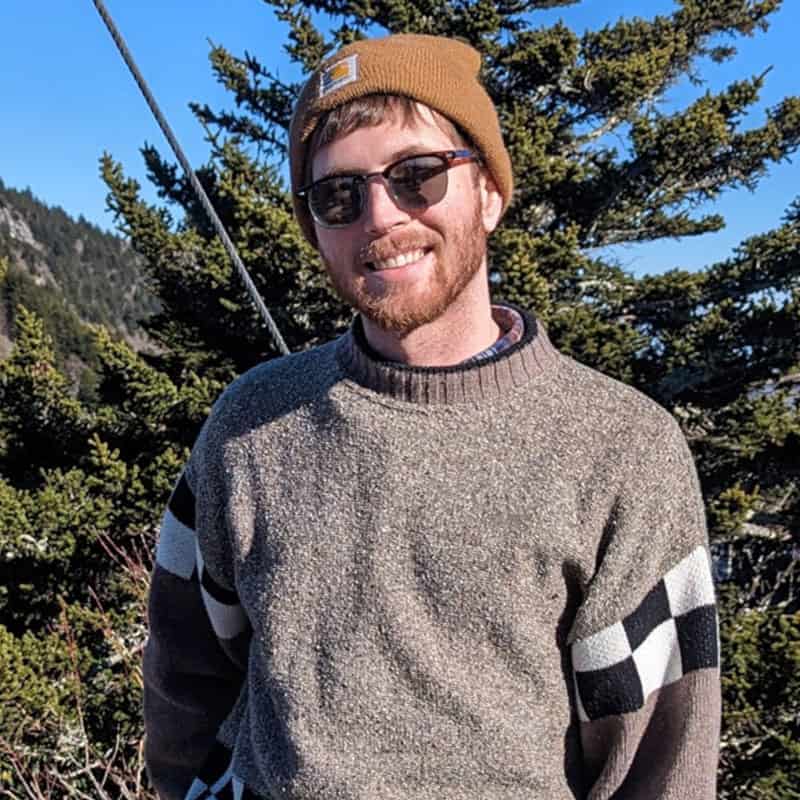 Innovative student at Pensacola State College enjoying outdoor activities Young man with sunglasses and beanie smiling outdoors in nature.