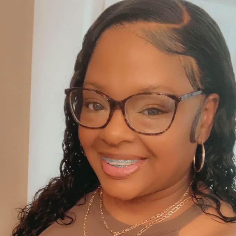 Anetia Dukes smiling with glasses and jewelry at Pensacola State College campus Anetia Dukes, college student, smiling with glasses and jewelry at Pensacola State College campus.