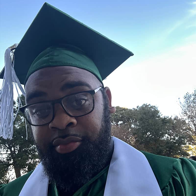 Graduation Cap and Gown – Tyriq Flowers Graduate wearing cap and gown at Pensacola State College graduation ceremony.
