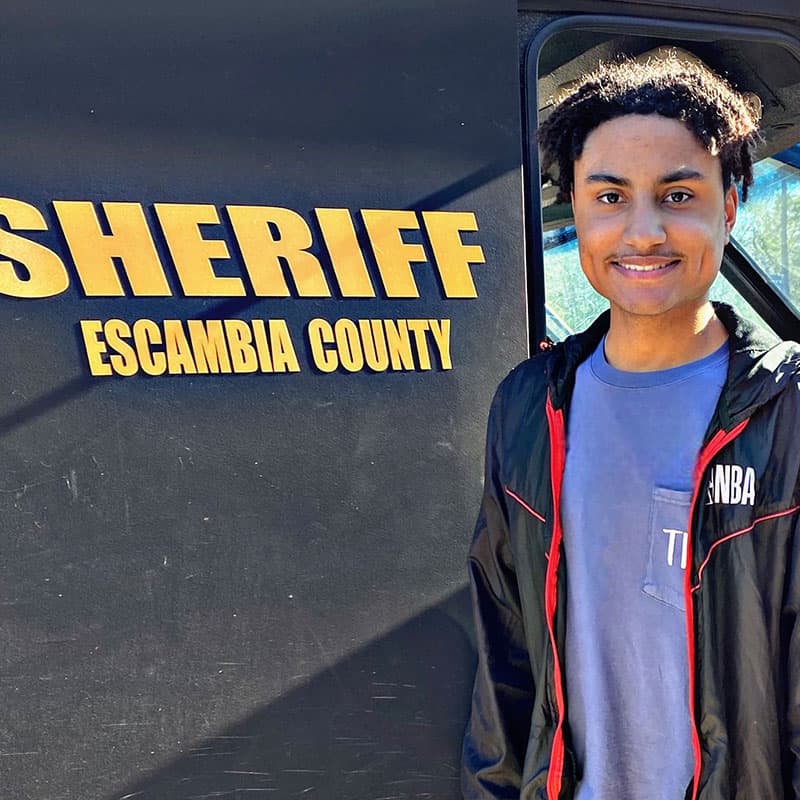 Troy Mims at Escambia County Sheriff’s Office vehicle for community engagement Troy Mims standing next to Escambia County Sheriff's vehicle, highlighting community policing effort.