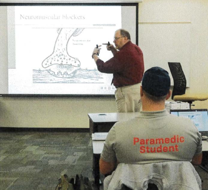 Teacher explains projector slide of medical procedures.