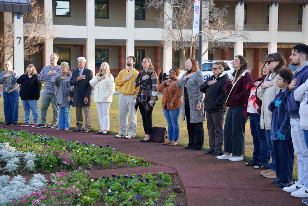 PSC staff gather for the Pledge of Allegiance at the flagpole on the Pensacola campus.