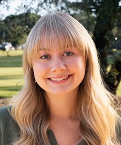 Student smiling outdoors at Pensacola State College campus, Florida.
